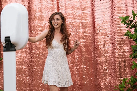 Woman using a photo booth with a sequin backdrop.