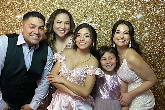 Family portrait at a Quinceañera with the birthday girl in a pink dress and tiara.
